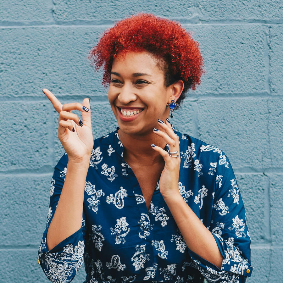 Photo of woman smiling while pointing on her right side by Eye for Ebony on Unsplash